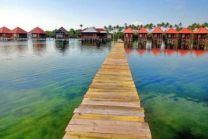 Jembatan kayu dan rumah-rumah panggung di atas laut jernih Pulau Osi, Seram Bagian Barat