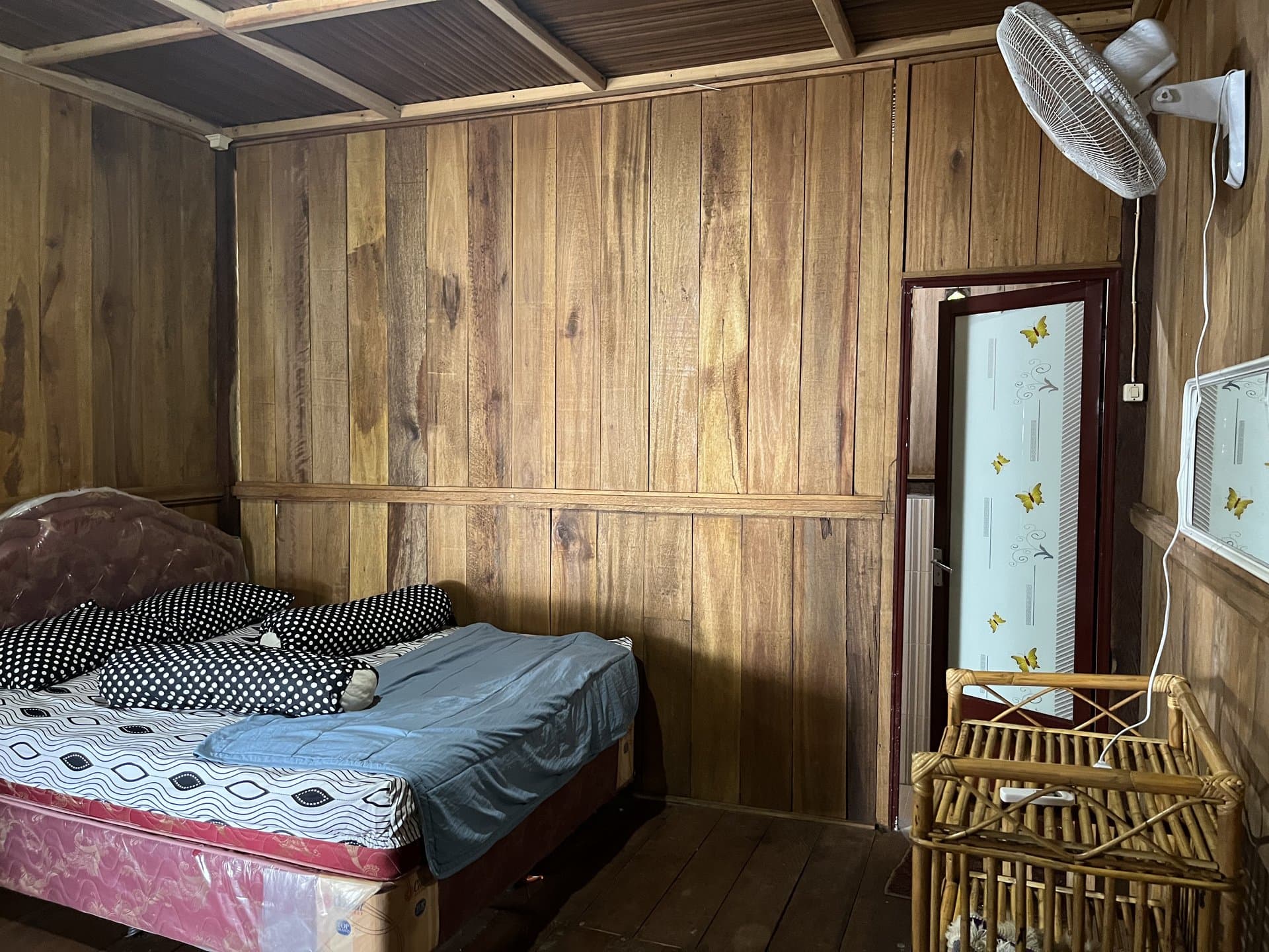 Grand Villa bedroom at Shafira Resort with timber walls, a bed, and a fan