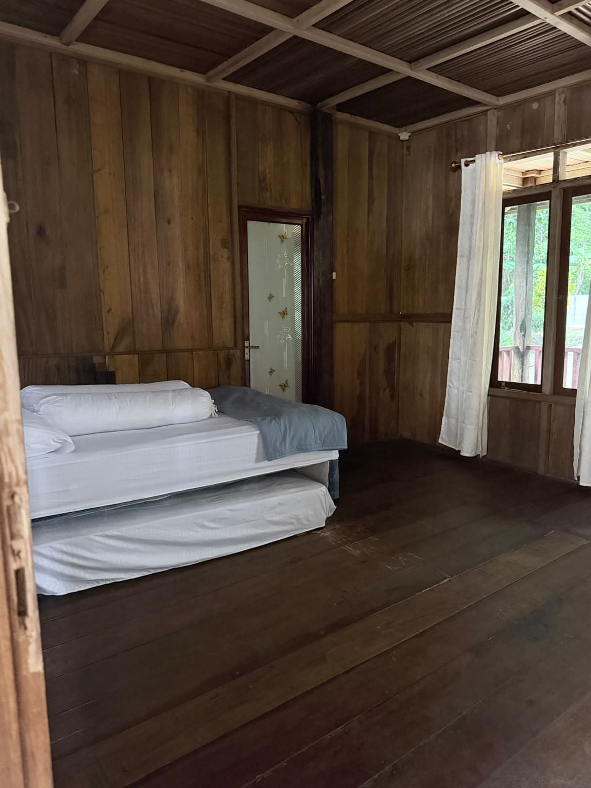Kamar kedua Vila Besar Shafira Resort dengan ranjang sorong, lantai kayu, dan jendela bertirai